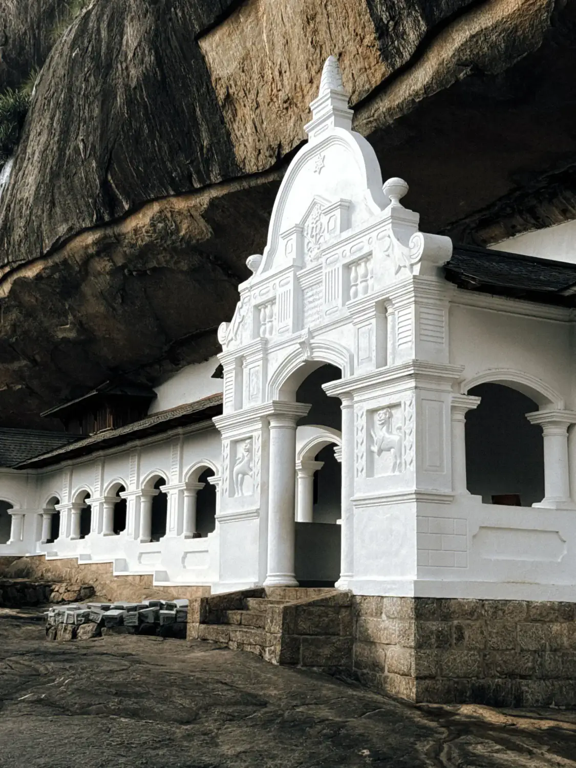 The white facade of the Dambulla cave temple set against a rocky hill.
