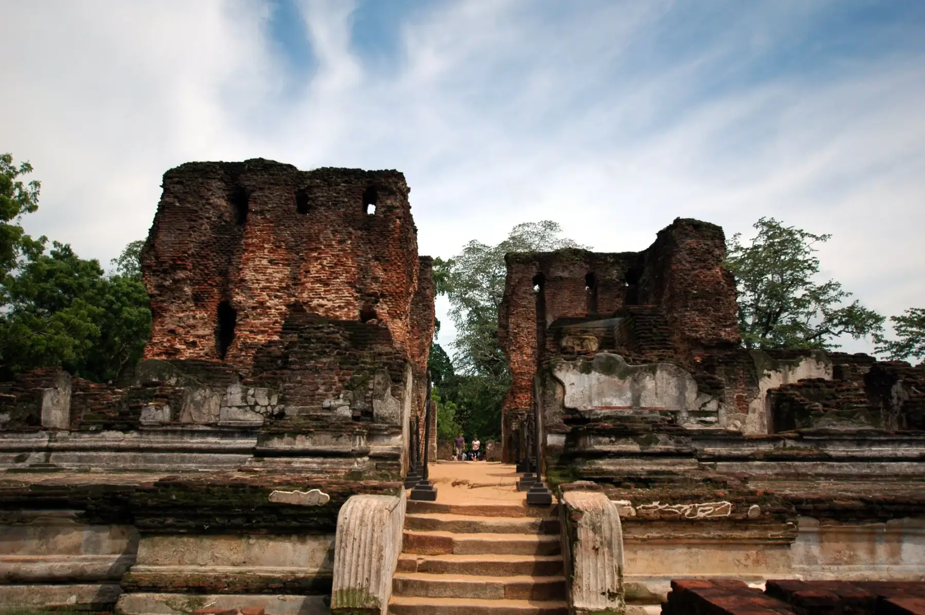 Brick ruins of the ancient city of Polonnaruwa in green parkland.