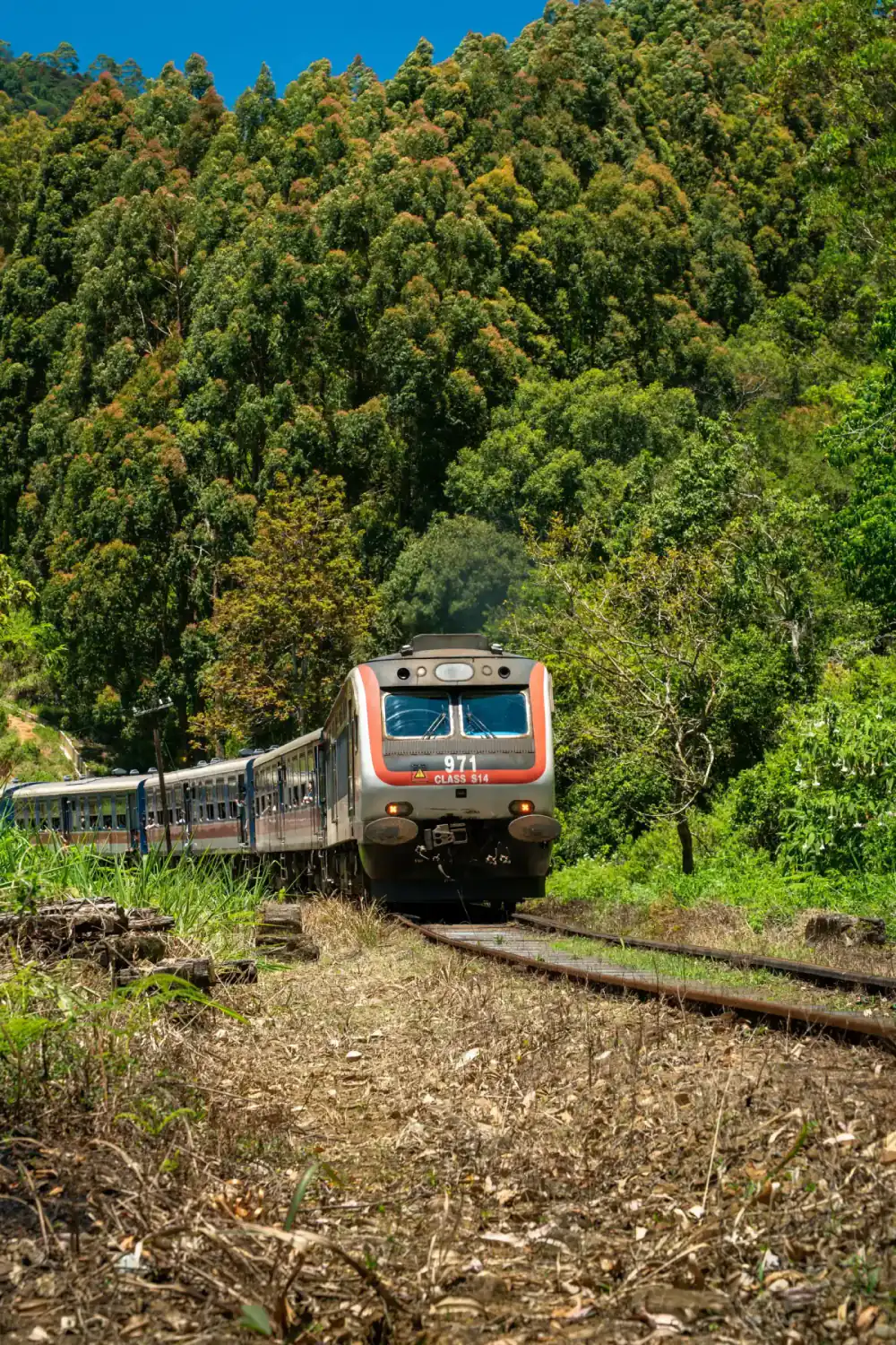 A train travelling through steep green mountains in Sri Lanka's hill country.